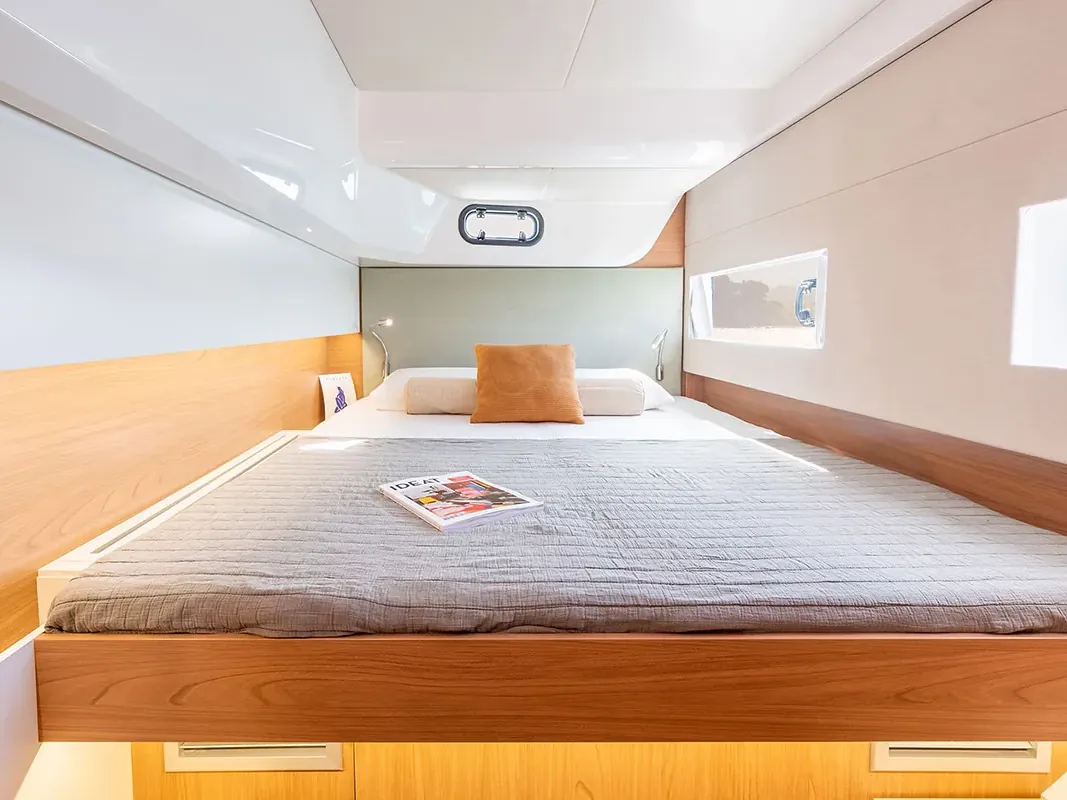 Cabin with a double bed, light wood trim and a round porthole window