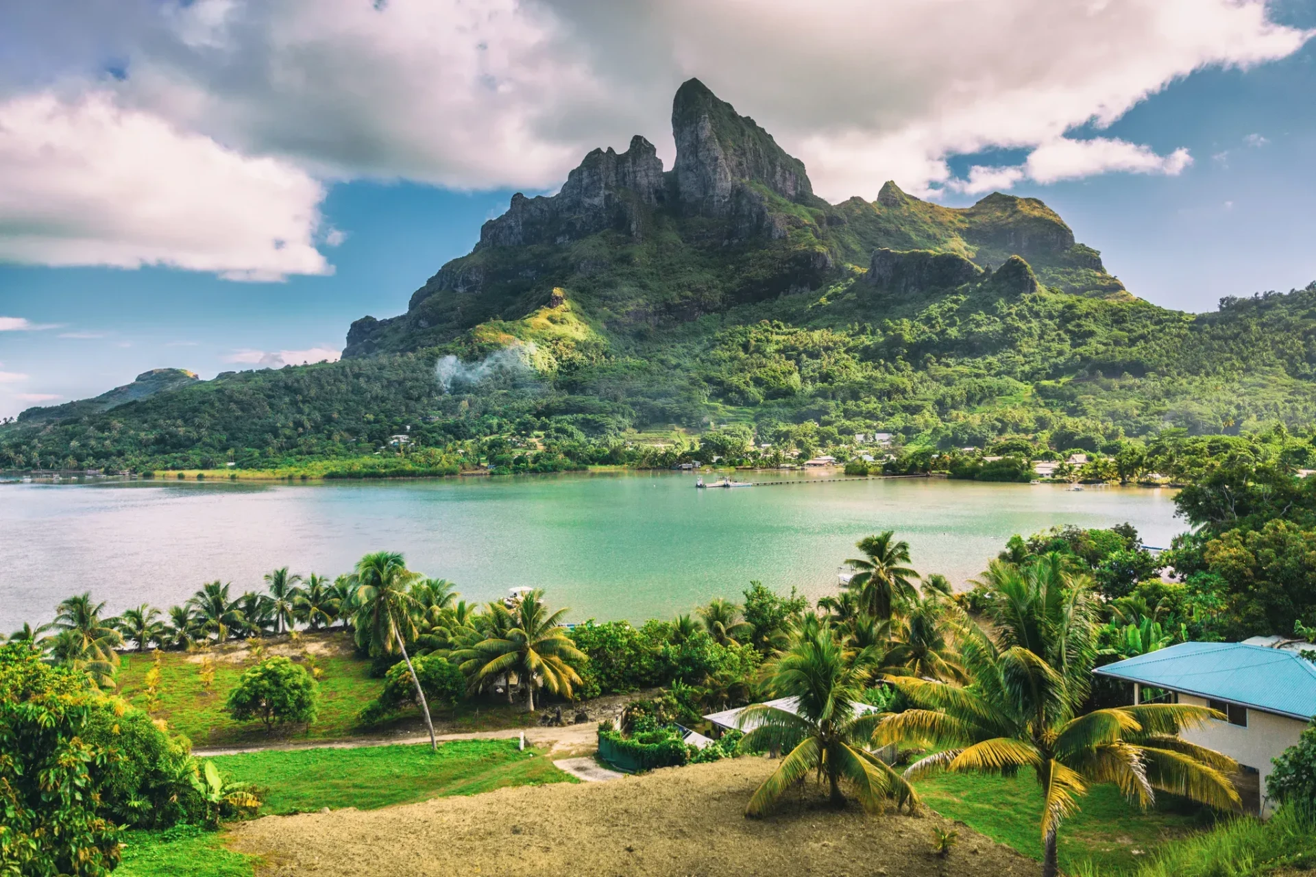 Green volcanic mountain above a palm-lined lagoon